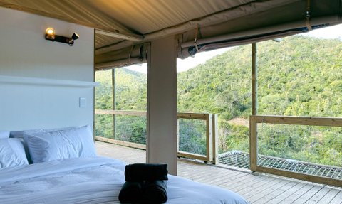 Ein gemütliches Schlafzimmer mit einem großen Bett und frischen weißen Bettlaken, das auf eine grüne Landschaft blickt.