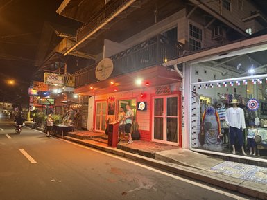 Bunt beleuchtete Geschäfte und Menschen stehen auf einer belebten Straße in einem lebhaften Nachtmarkt von Bocas del Toro.