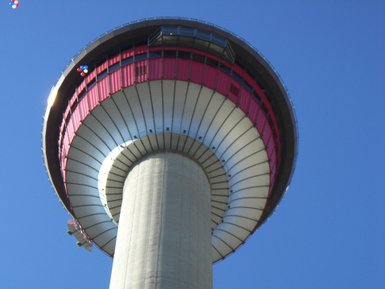 Der Calgary Tower ragt majestätisch in den blauen Himmel, mit einer markanten rot-weißen Aussichtsplattform oben.