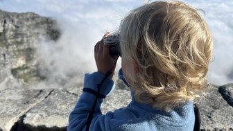 Junge schaut mit Fernglas über die Landschaft vom Tafelberg – Südafrika mit Kindern