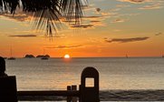 Ein atemberaubender Sonnenuntergang über dem Meer, mit sanften Wellen und einem Boot in der Ferne.