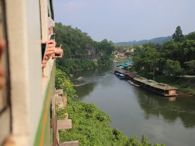 Blick aus dem Waggon waehrend der Eisenbahnfahrt vorbei am River Kwai - Thailand Reise mit Kindern 