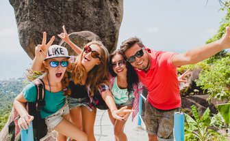 Jugendliche halten fröhlich ein Selfie vor der Dschungellandschaft – Thailand Familienreise