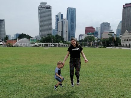 Mutter und Kind springen auf einer grünen Wiese in Kuala Lumpur – Malaysia & Borneo Familienreise