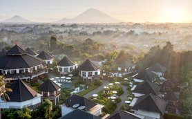 Eine atemberaubende Aussicht auf ein Resort mit traditionellen Dächern, umgeben von üppiger Natur und Bergen im Hintergrund.