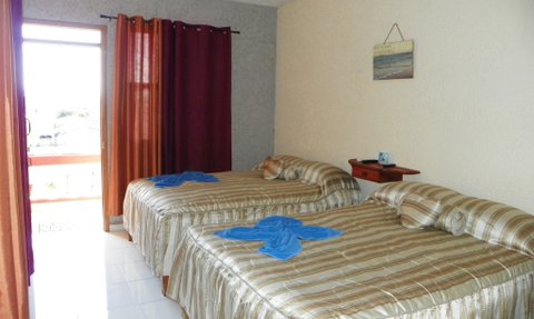 Das Schlafzimmer verfügt über zwei Einzelbetten mit gestreiften Bettdecken und blauen Handtüchern, die ordentlich drapiert sind.