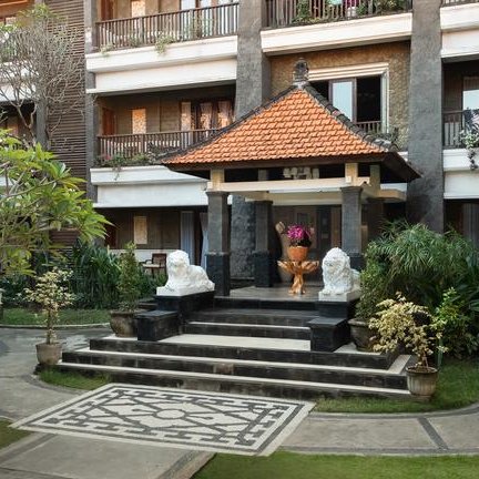 Ein einladender Eingang zu einem tropischen Resort, umgeben von üppigem Grün und kunstvollen Steinlöwen.