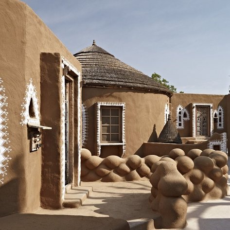 Eine malerische Ansicht eines traditionellen Hotels mit erdigen Wänden und kunstvollen weißen Verzierungen.