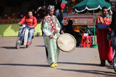 Musiker spielt auf einer Trommel auf dem Djemaa el Fna Platz in Marrakesch – Marokko mit Kindern