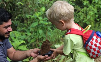 Kleinkind und Guide beim Baumpflanzen in La Tigra – Costa Rica Familienreise