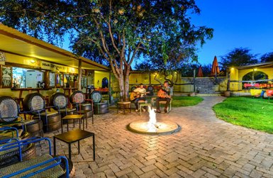 Eine gemütliche Bar mit Lagerfeuer im Innenhof, zwei Musiker spielen Gitarre - Namibia Familienreise