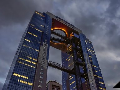 Ein beeindruckendes Hochhaus in Osaka, das durch seine einzigartige Architektur und die leuchtende Öffnung im oberen Bereich besticht.