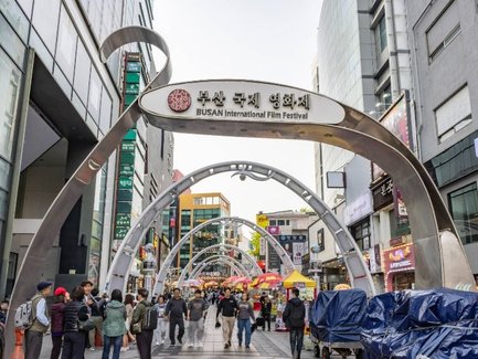 Eine belebte Straße während des Busan International Film Festivals, mit Menschen, die sich unter den geschwungenen Bögen bewegen.
