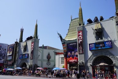 Die beeindruckende Fassade des TCL Chinese Theatre in Hollywood, umgeben von Menschen und bunten Sonnenschirmen.