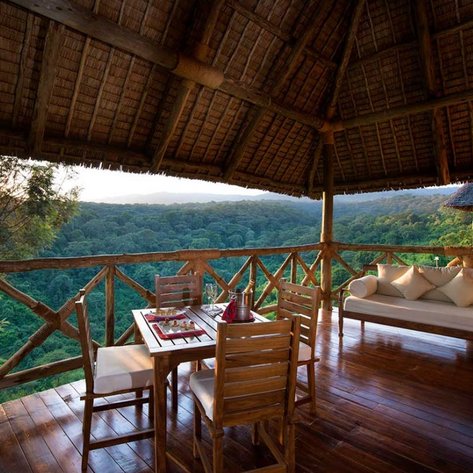 Eine einladende Veranda mit Holzstühlen und einem Tisch, der auf eine üppige grüne Landschaft blickt, ideal für Entspannung.