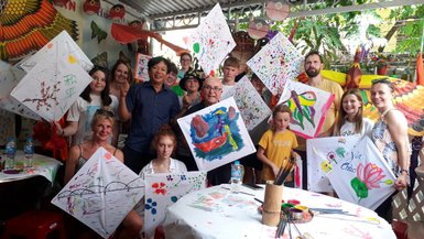 Eine Gruppe von Menschen lächelt und hält stolz ihre bunten Drachen, umgeben von einer lebhaften, dekorierten Umgebung.