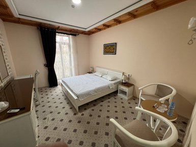 Ein helles Hotelzimmer mit einem großen Bett, einem Tisch und zwei Stühlen, das eine gemütliche Atmosphäre ausstrahlt.