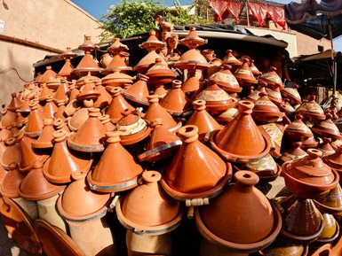 Ein Haufen traditioneller marokkanischer Tajine-Töpfe, die übereinander gestapelt in einem lebhaften Markt stehen.