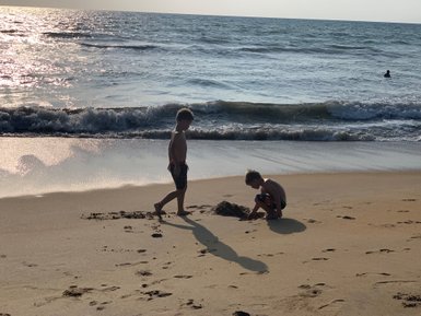 Zwei Kinder sitzen am Strand der Südküste und formen mit ihren Händen Sandburgen im weichen Sand – Sri Lanka Reise mit Kindern