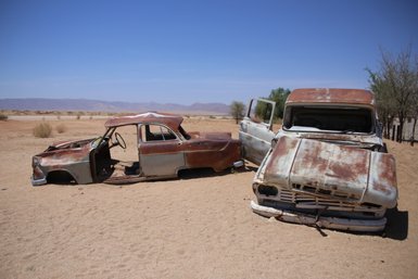 Zwei rostige Autos stehen verlassen in einer Wüste - Namibia mit Kindern