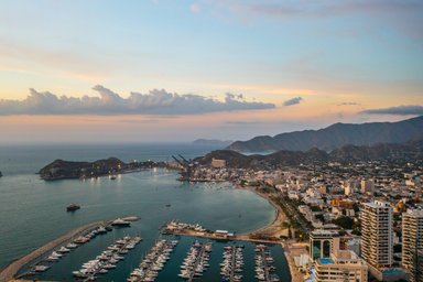 Ein atemberaubender Blick auf den Hafen von Santa Marta, umgeben von Bergen und einem sanften Sonnenuntergangshimmel.