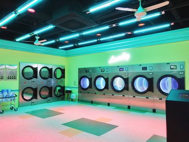 Ein moderner Waschsalon mit leuchtend grünen Wänden und bunten Neonlichtern, die eine einladende Atmosphäre schaffen.