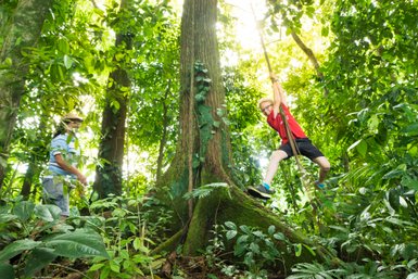 Kind spielt an einer Liane im üppigen Regenwald – Costa Rica Familienreise