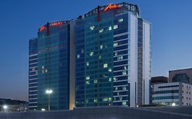 Das Asti Hotel in Busan erstrahlt in der Dämmerung, mit leuchtenden Fenstern und einem modernen Glasdesign.
