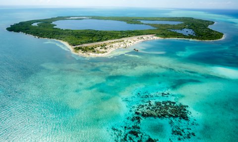Eine atemberaubende Luftaufnahme einer tropischen Insel mit üppigem Grün und klarem, türkisfarbenem Wasser umgeben.