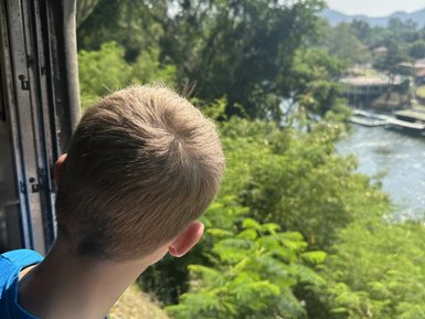 Junge blickt aus Fenster bei Zugfahrt mit Death Train - Thailand mit Kindern