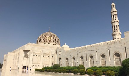 Die beeindruckende Moschee mit einer großen Kuppel und einem hohen Minarett steht vor einem klaren blauen Himmel.