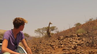 Ein Junge beobachtet gespannt eine Giraffe - Namibia mit Jugendlichen