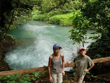 Fröhliche Kinder vor dem türkisblauen Rio Celeste – Costa Rica mit Kindern