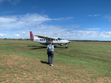 Reisende steht mit Rucksack vor einem kleinen Safariflugzeug – Tansania Reise mit Kindern