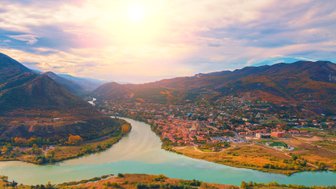 Eine malerische Aussicht auf die Stadt Mtskheta, umgeben von sanften Hügeln und dem glitzernden Fluss, der sich schlängelt.