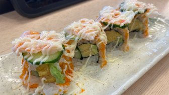 Eine kunstvoll angerichtete Sushi-Platte mit bunten Rollen, die mit Mayonnaise und Garnelen belegt sind.