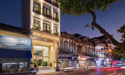 Das Soleil Boutique Hotel strahlt in der Dämmerung mit seiner eleganten Fassade und den warmen Lichtern, umgeben von lebhaften Straßen.