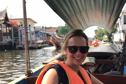Eine Frau mit Sonnenbrille und orangefarbener Schwimmweste lächelt fröhlich auf einem Boot in einem Kanal.