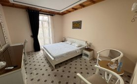 Ein helles Hotelzimmer mit einem großen Bett, einem Tisch und zwei Stühlen, das eine gemütliche Atmosphäre ausstrahlt.
