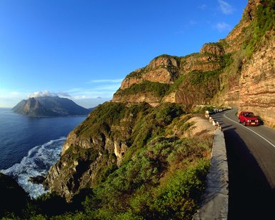 Fahrzeug fährt entlang des Chapman's Peak Drive mit Blick auf den Atlantik – Garden Route Reise mit Kindern