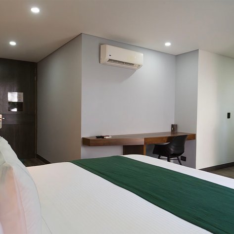 Ein modernes Hotelzimmer mit einem großen Bett, einem Schreibtisch und einer stilvollen Holzverkleidung an der Wand.