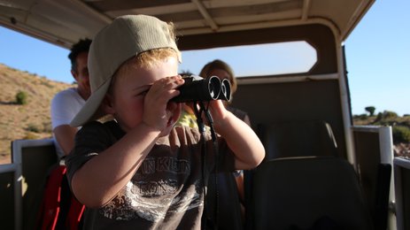 Kind beobachtet mit einem Fernglas während einer Safari – Südafrika Reise mit Kindern