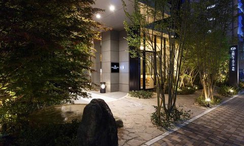 Der Eingangsbereich eines modernen Hotels in Osaka, umgeben von sanften Lichtern und üppigem Grün.