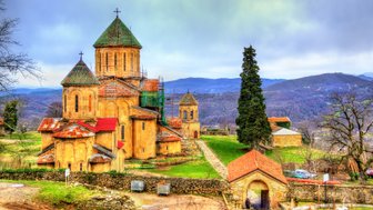 Eine alte Klosteranlage mit beeindruckender Architektur, umgeben von sanften Hügeln und bewaldeten Landschaften.