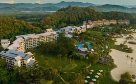 Ein luxuriöses Resort eingebettet in üppige Natur, mit mehreren langen Gebäuden und einem glitzernden Poolbereich.