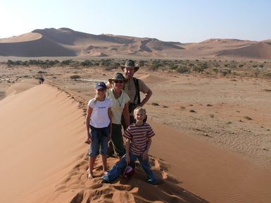 Eine Familie steht auf einer Düne  in der Wüste - Namibia Urlaub mit Kindern