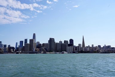 Die Skyline von San Francisco zeigt moderne Wolkenkratzer und den ikonischen Transamerica-Pyramid, umgeben von Wasser.