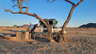 Ein Jeep mit Dachzelt steht neben einem aufgebauten Camp - Namibia mit Jugendlichen