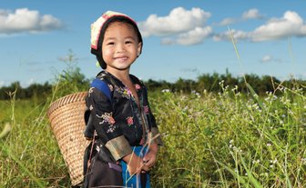 Einheimisches Kind zwischen grünen Teesträuchern in einer Teeplantage – China mit Kindern