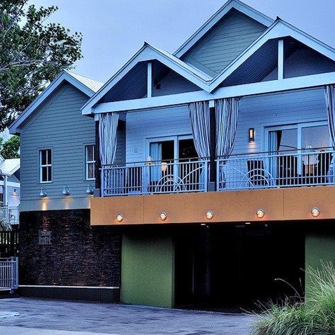 Ein modernes Haus in Florida mit einem Balkon, der von eleganten Vorhängen umgeben ist, und einem begrünten Eingangsbereich.